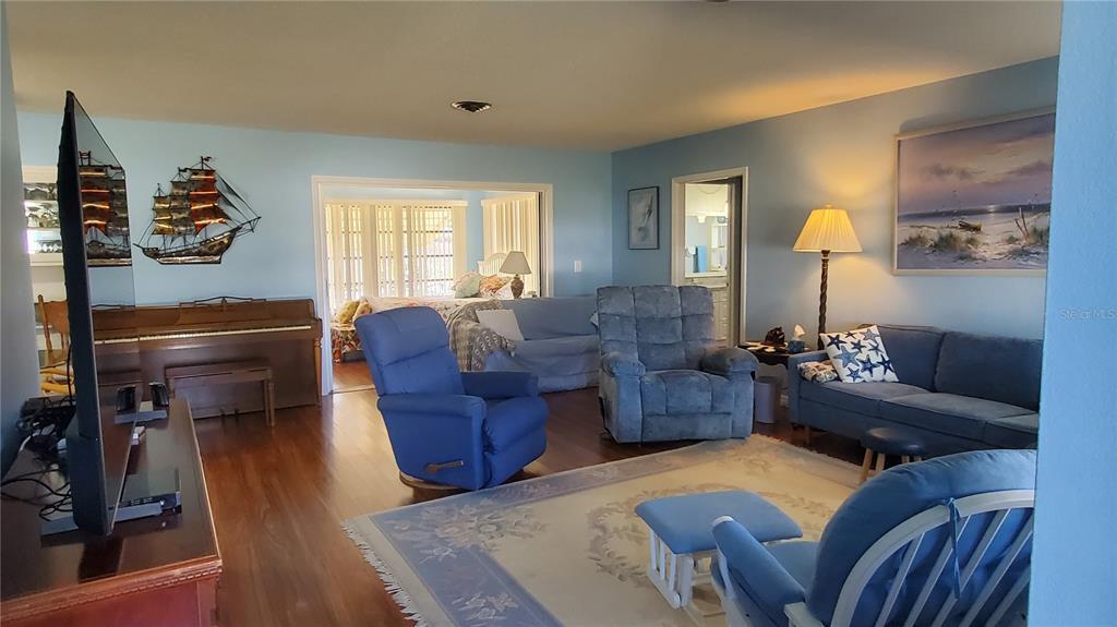 A living room features blue walls, hardwood floors, a piano, and several blue seating pieces — 1765 LORALIN DRIVE, ENGLEWOOD, FL