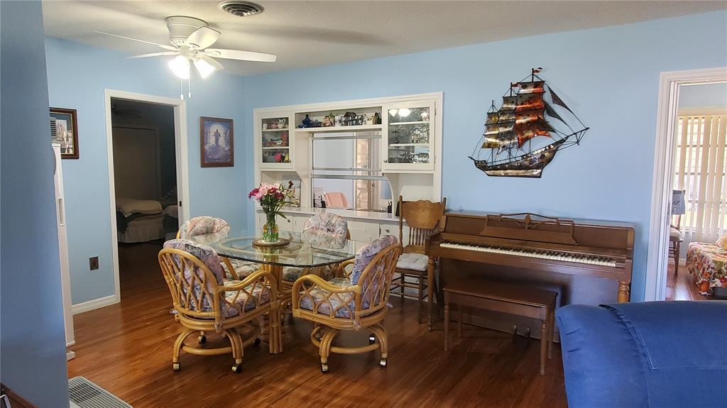A dining area with a glass table, wicker chairs, a piano, and light blue walls — 1765 LORALIN DRIVE, ENGLEWOOD, FL