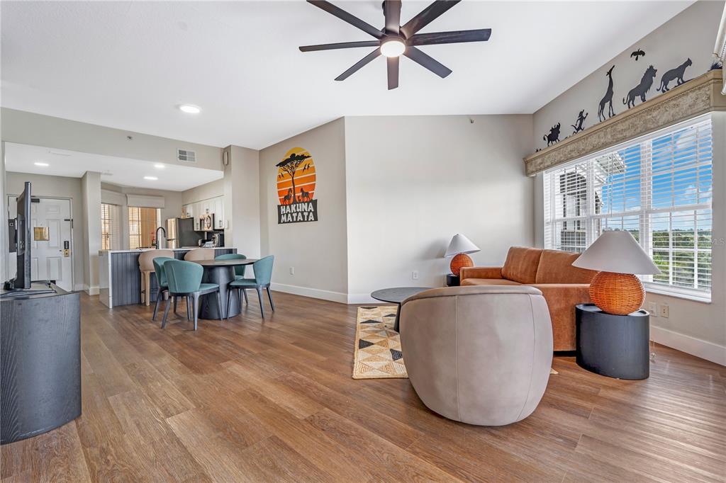 A living room and dining area feature wood-look flooring, a ceiling fan, and animal-themed decor — 8601 WORLDQUEST BOULEVARD UNIT 3506, ORLANDO, FL