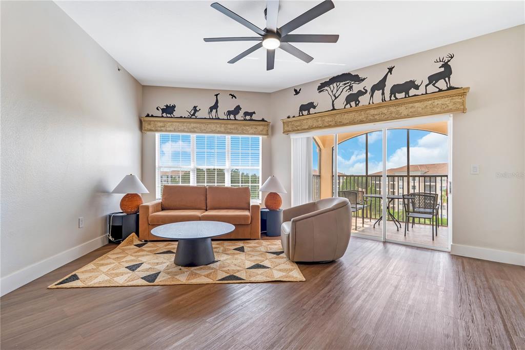A living room features a brown sofa, a round coffee table, and safari-themed wall decals — 8601 WORLDQUEST BOULEVARD UNIT 3506, ORLANDO, FL