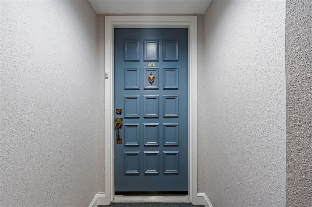 A blue front door with a brass knocker and the number 406 is centered — 6372 PALMA DEL MAR BOULEVARD S UNIT 406, ST PETERSBURG, FL