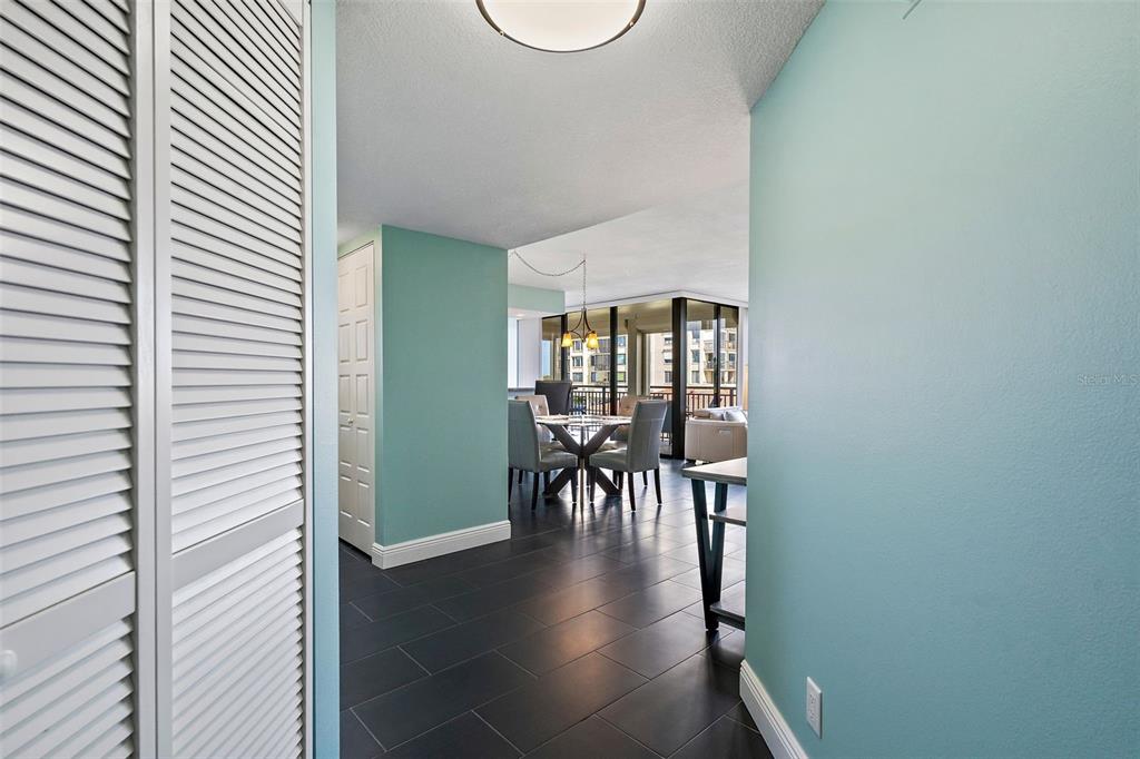 A view from a hallway into a dining area with dark tile flooring and windows — 6372 PALMA DEL MAR BOULEVARD S UNIT 406, ST PETERSBURG, FL
