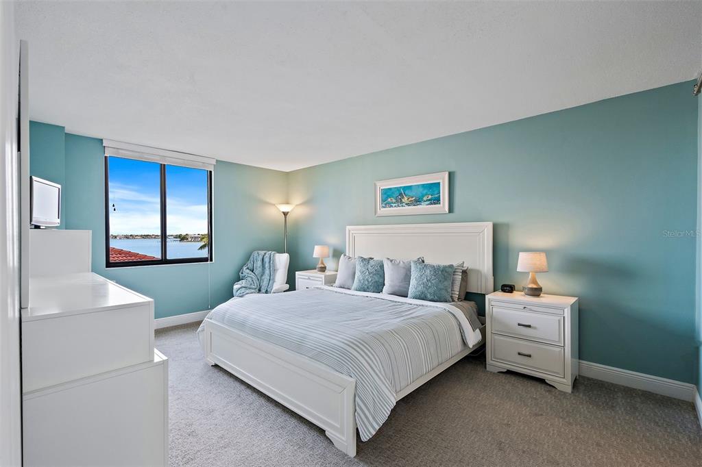 A bedroom with a white bed, matching nightstands, and a window overlooking the water — 6372 PALMA DEL MAR BOULEVARD S UNIT 406, ST PETERSBURG, FL