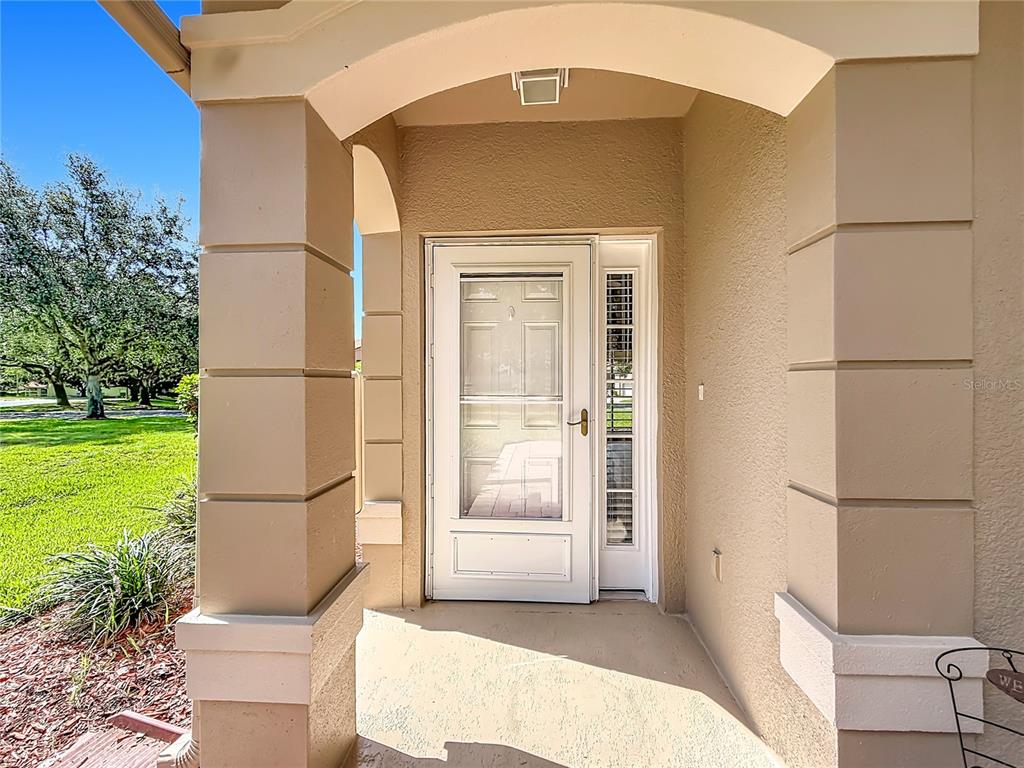 A tan covered entryway features a white storm door with a side light window — 5281 BOWLINE COURT, OXFORD, FL