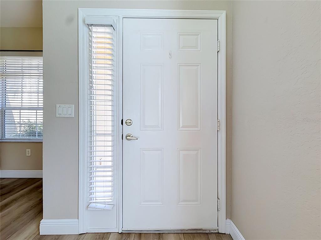 A white front door with a side window and blinds stands in a neutral-walled entryway — 5281 BOWLINE COURT, OXFORD, FL