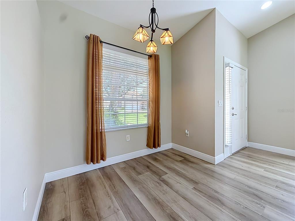 A dining area features wood-look flooring, a window with gold curtains, and a pendant light — 5281 BOWLINE COURT, OXFORD, FL