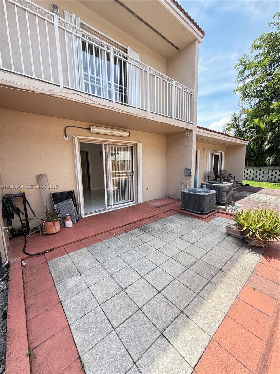 A two-story building exterior features a tiled patio, sliding glass doors, and two air conditioning units — 6926 NW 166th Ter # 1302, Miami Lakes FL 33014, MIAMI LAKES, FL
