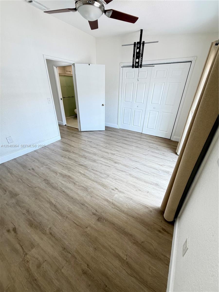 A bedroom features light wood-look flooring, a ceiling fan, and a closet with white doors — 6926 NW 166th Ter # 1302, Miami Lakes FL 33014, MIAMI LAKES, FL