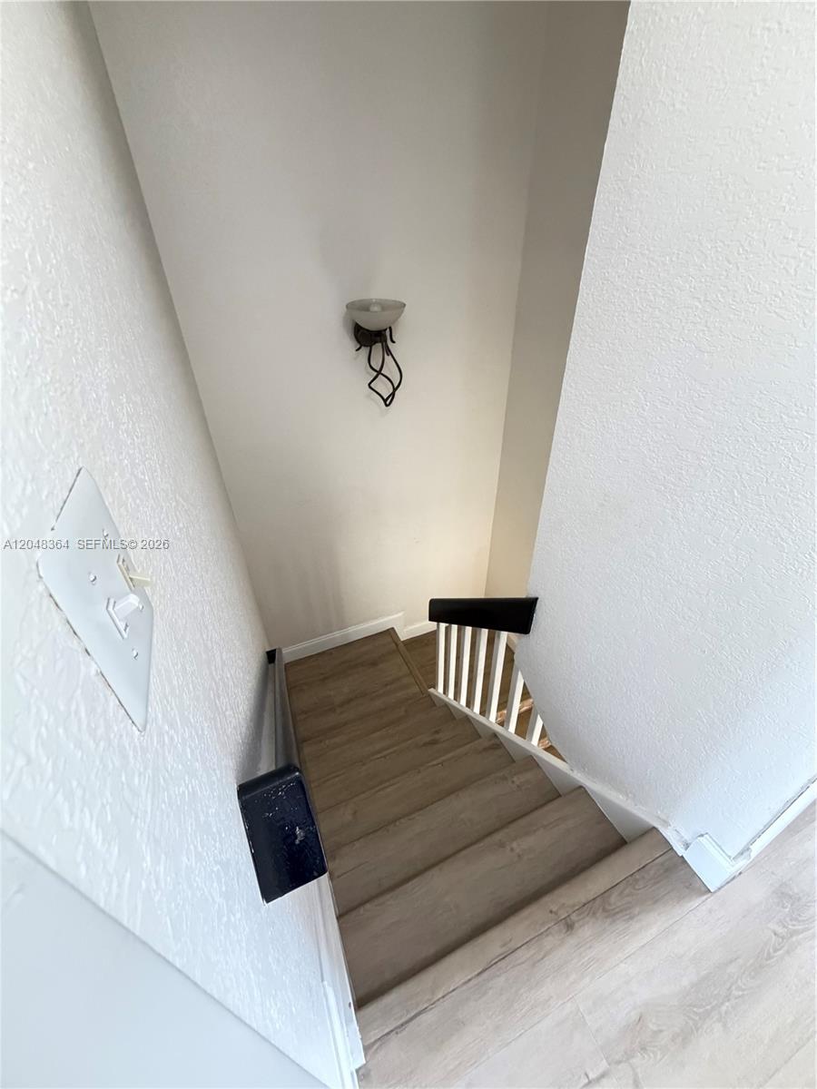 A wooden staircase with a black handrail and white balusters leads downward — 6926 NW 166th Ter # 1302, Miami Lakes FL 33014, MIAMI LAKES, FL