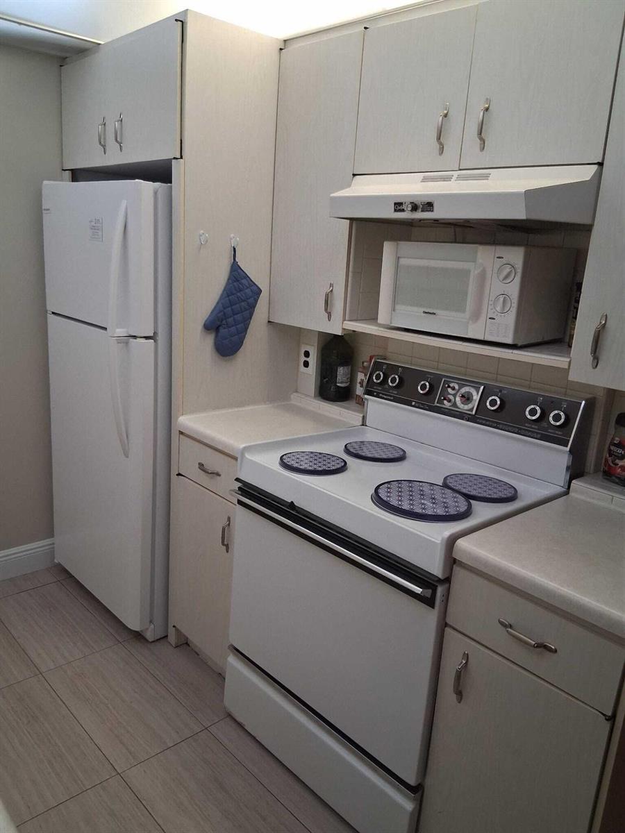 A kitchen featuring white cabinets, a white refrigerator, a white electric stove, and a microwave — 4023 Newport H, Deerfield Beach FL 33442, DEERFIELD BEACH, FL