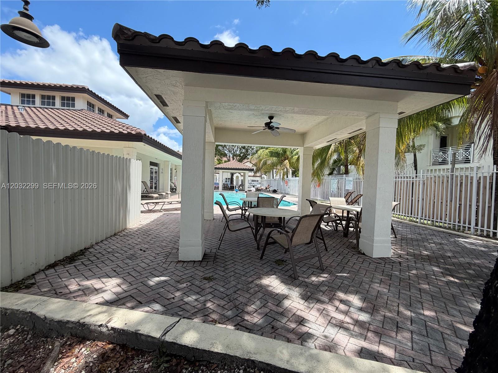 A covered patio with a dining set overlooks a swimming pool and a residential building — 8802 NW 109th Ct # 607, Doral FL 33178, DORAL, FL