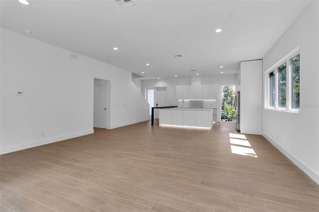 A modern, open-concept kitchen and living area with white cabinets and light wood flooring — 2516 BROWNING STREET, SARASOTA, FL