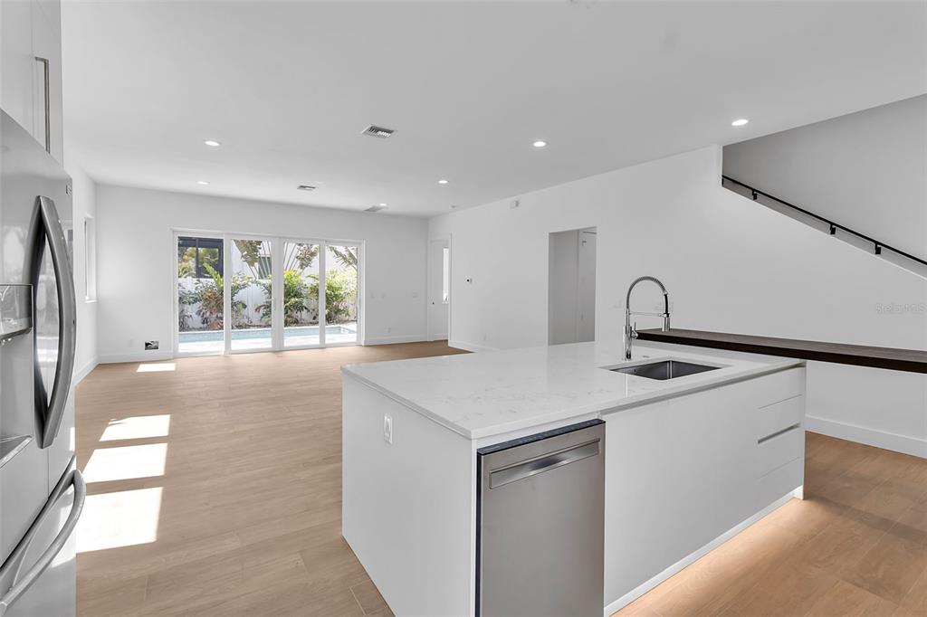 A modern kitchen with a white island and stainless steel appliances overlooks a living area — 2516 BROWNING STREET, SARASOTA, FL
