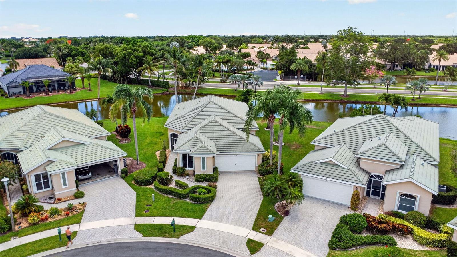 An aerial view shows three suburban houses with light-colored roofs and driveways near a pond — 7760 Carrington Court, Boynton Beach FL 33472, BOYNTON BEACH, FL