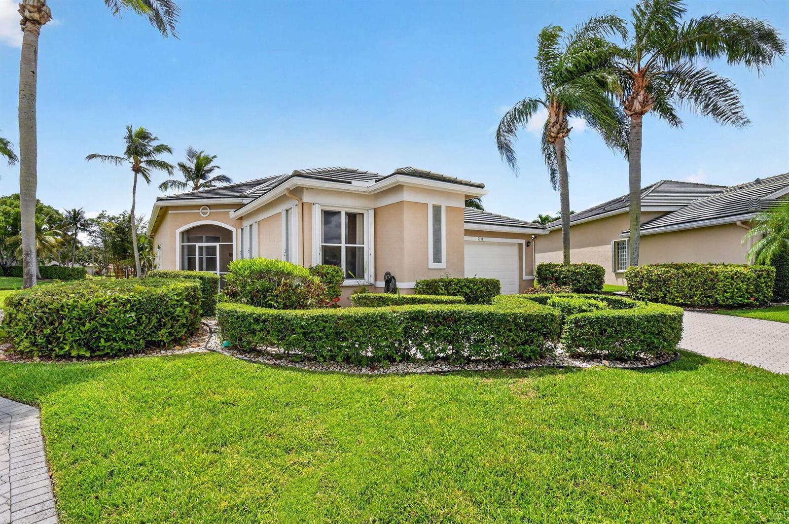 A single-story tan house with a screened entryway, a garage, and manicured hedges in front — 7760 Carrington Court, Boynton Beach FL 33472, BOYNTON BEACH, FL