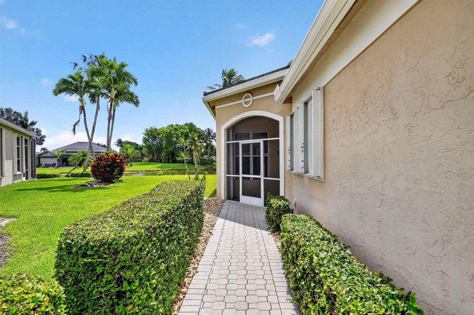 A paved walkway leads to a screened entryway beside a house with manicured hedges — 7760 Carrington Court, Boynton Beach FL 33472, BOYNTON BEACH, FL