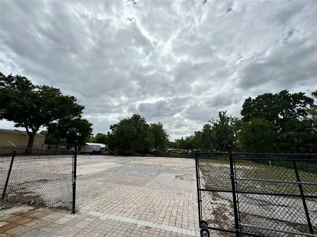 A fenced, paved lot with trees under a cloudy sky — 580 FAIRVILLA ROAD, ORLANDO, FL