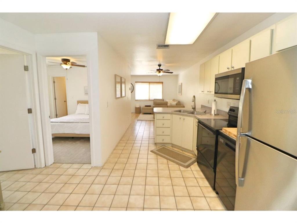 A kitchen with tile flooring and stainless steel appliances opens into a living area — 906 E 11TH AVENUE, NEW SMYRNA BEACH, FL