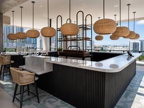 An outdoor bar features a stone countertop, dark slatted base, and multiple woven pendant lights — 20 NE 11th ST # 3207, Miami FL 33132, MIAMI, FL
