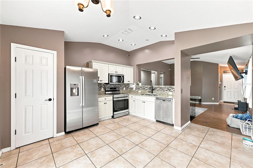 A kitchen with white cabinets, stainless steel appliances, and tan tile flooring — 5217 MANGO FRUIT STREET, SEFFNER, FL