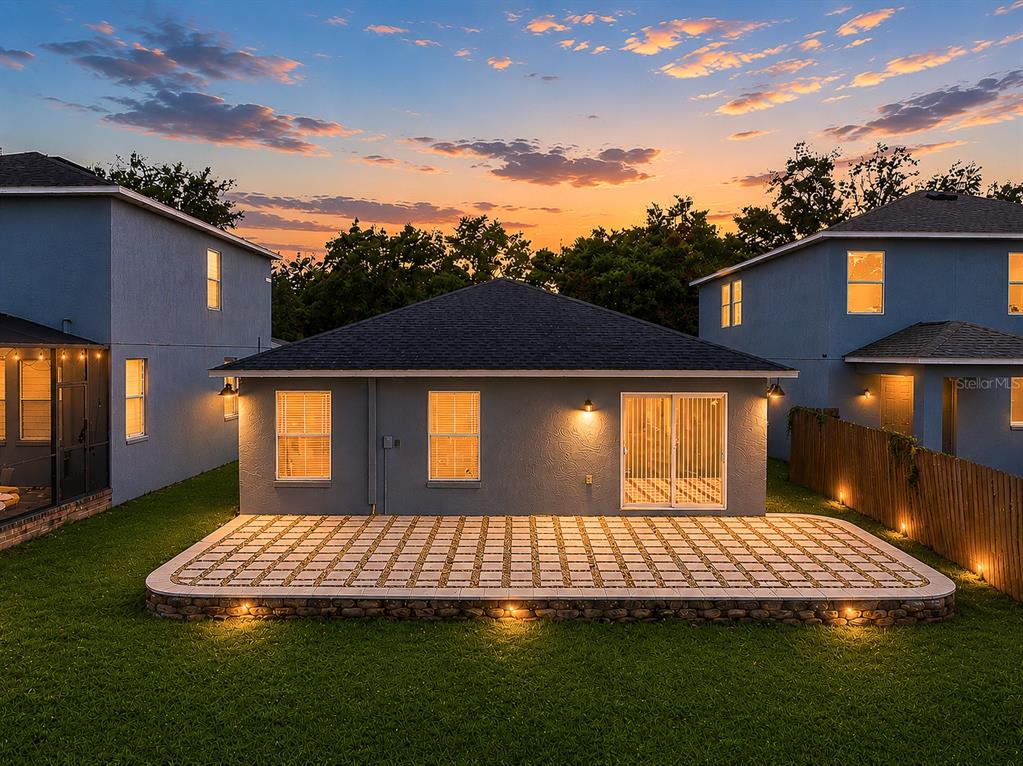 A rear view of a house at dusk featuring a paved patio and lawn — 5217 MANGO FRUIT STREET, SEFFNER, FL