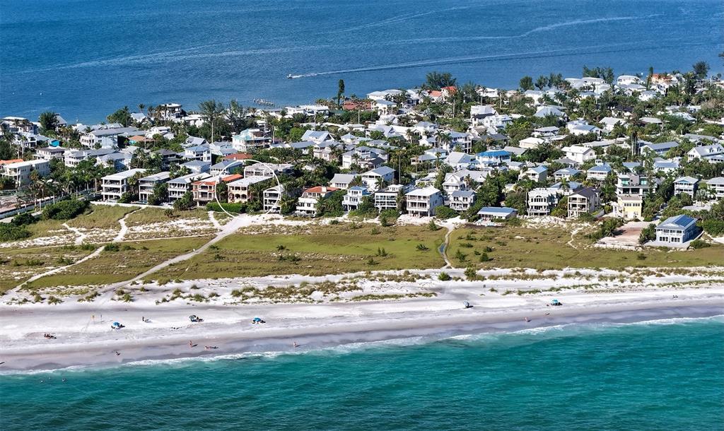 An aerial view of a coastal neighborhood with houses situated near a sandy beach — 801 N SHORE DRIVE, ANNA MARIA, FL