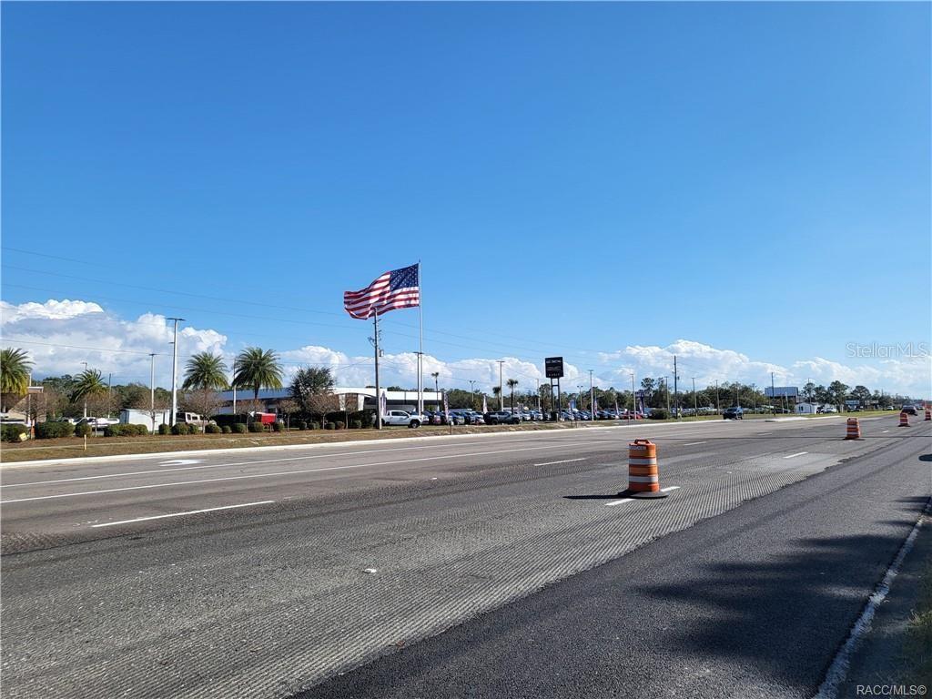 A large American flag flies over a car dealership along a multi-lane road — 1224 S SUNCOAST BOULEVARD, HOMOSASSA, FL
