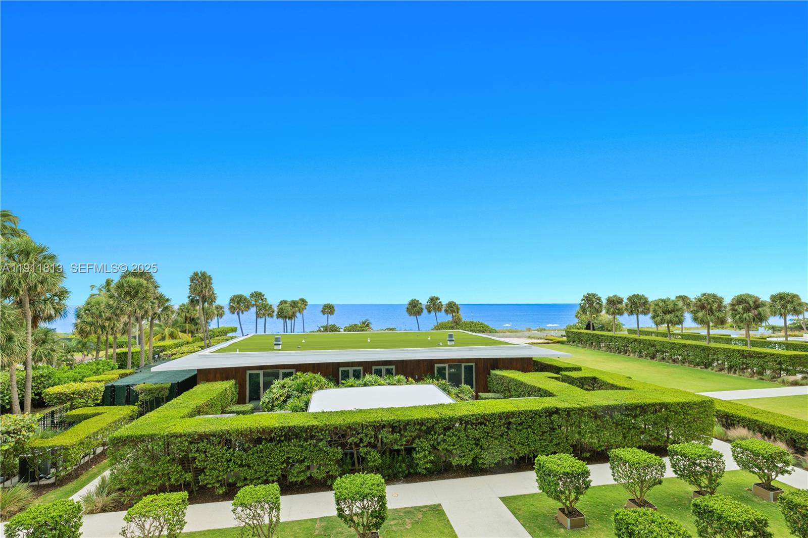 An exterior view shows a flat-roofed building surrounded by manicured hedges and palm trees — 350 E Ocean Dr # 301N, Key Biscayne FL 33149, KEY BISCAYNE, FL