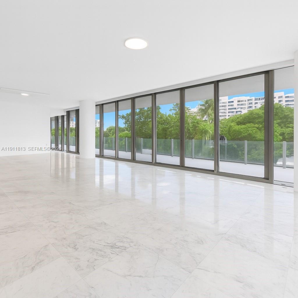 An empty room features white marble floors, a white ceiling, and floor-to-ceiling glass sliding doors — 350 E Ocean Dr # 301N, Key Biscayne FL 33149, KEY BISCAYNE, FL