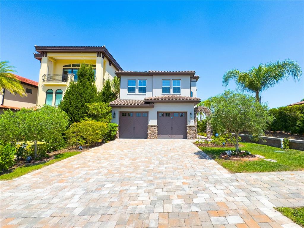 A two-story house with a paved driveway, two garage doors, and a tile roof — 16210 RAVENNA COURT, MONTVERDE, FL