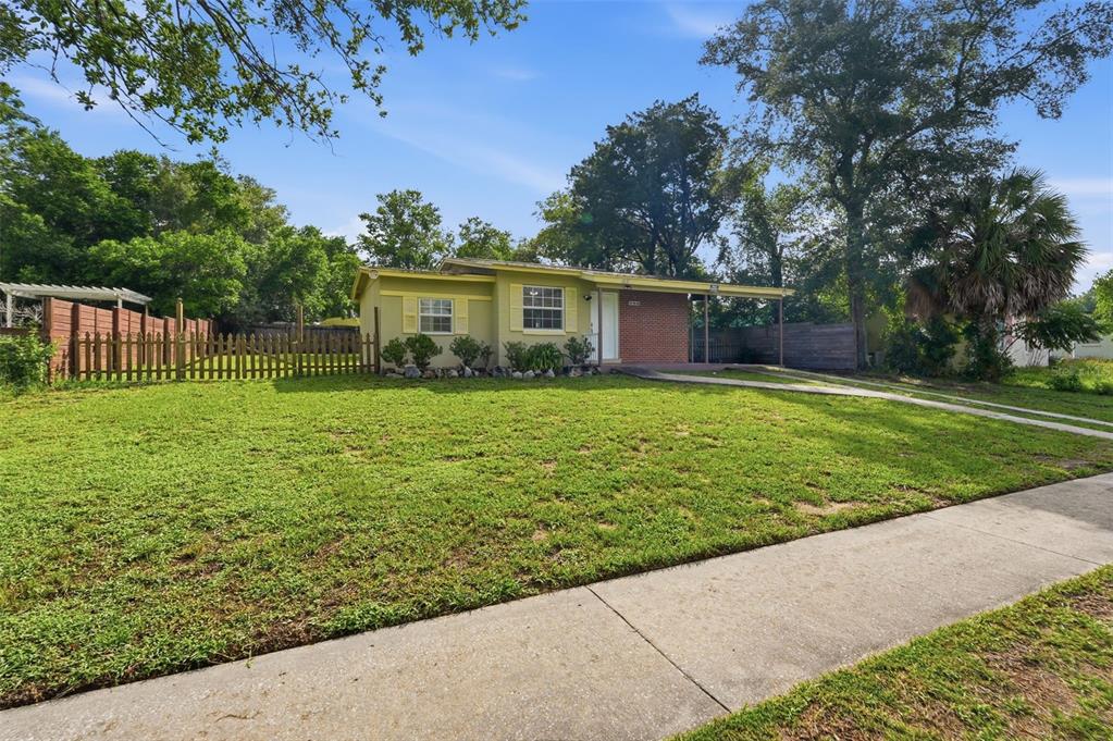 A single-story house with a brick facade and yellow siding sits behind a large lawn — 9447 N MILAM WAY, CITRUS SPRINGS, FL