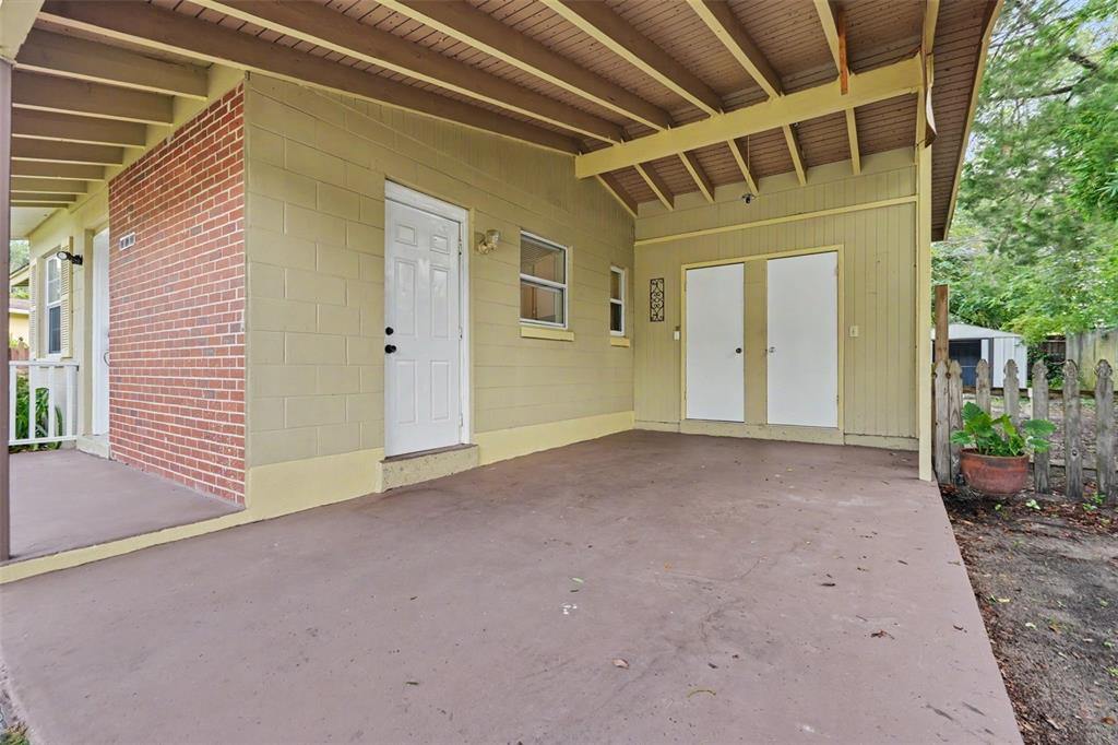 A covered concrete patio features a brick wall, a white door, and double storage doors — 9447 N MILAM WAY, CITRUS SPRINGS, FL