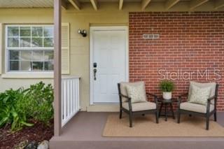 A front porch features two chairs, a small table, and a white door with brick — 9447 N MILAM WAY, CITRUS SPRINGS, FL