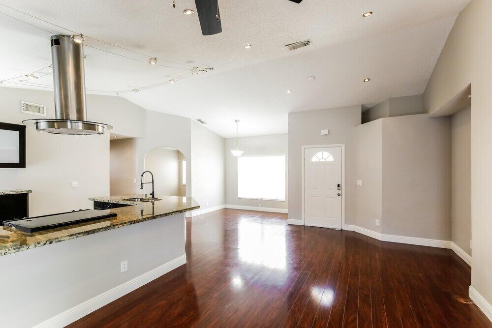 A kitchen with a granite island and stainless steel vent hood overlooks a living area — PEMBROKE PINES, FL