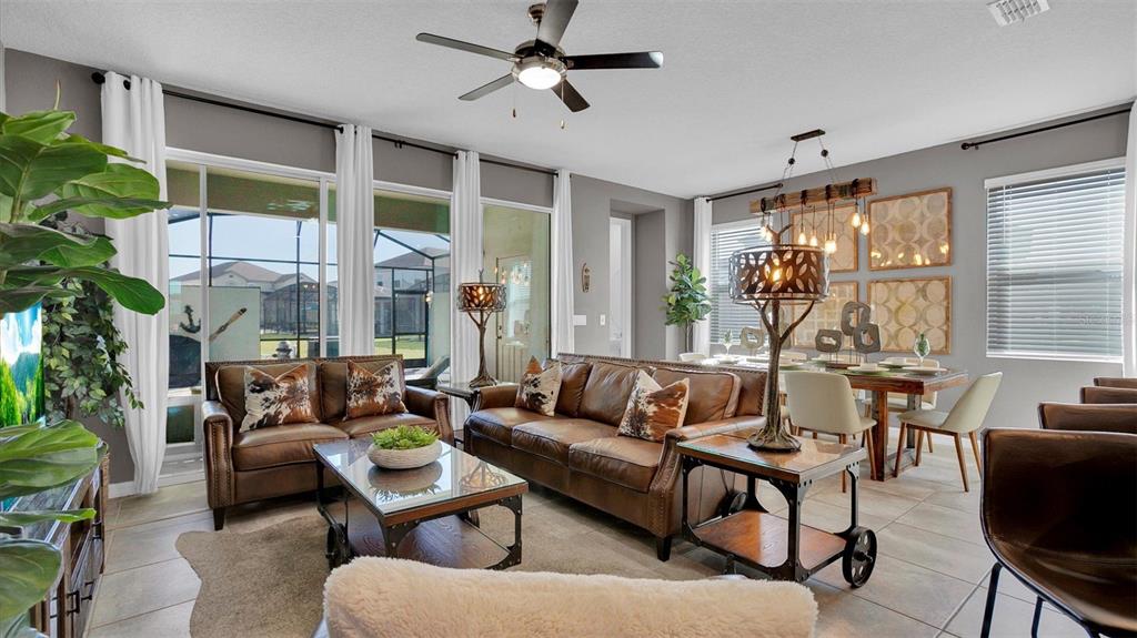 A living and dining area features leather sofas, a glass coffee table, and large windows — 2147 COOPER BELL PLACE, KISSIMMEE, FL