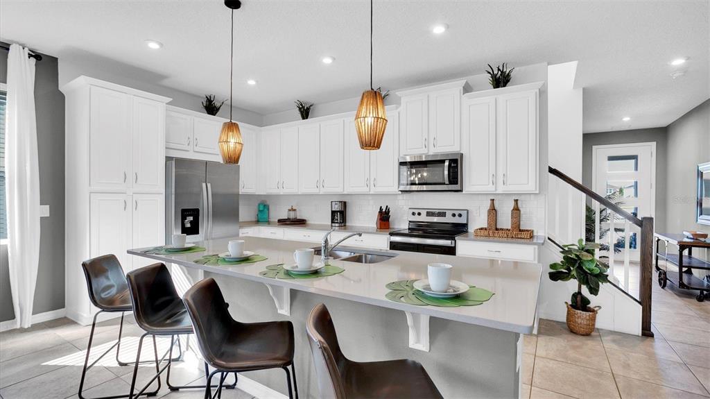 A modern kitchen features white cabinetry, stainless steel appliances, and a large central island — 2147 COOPER BELL PLACE, KISSIMMEE, FL