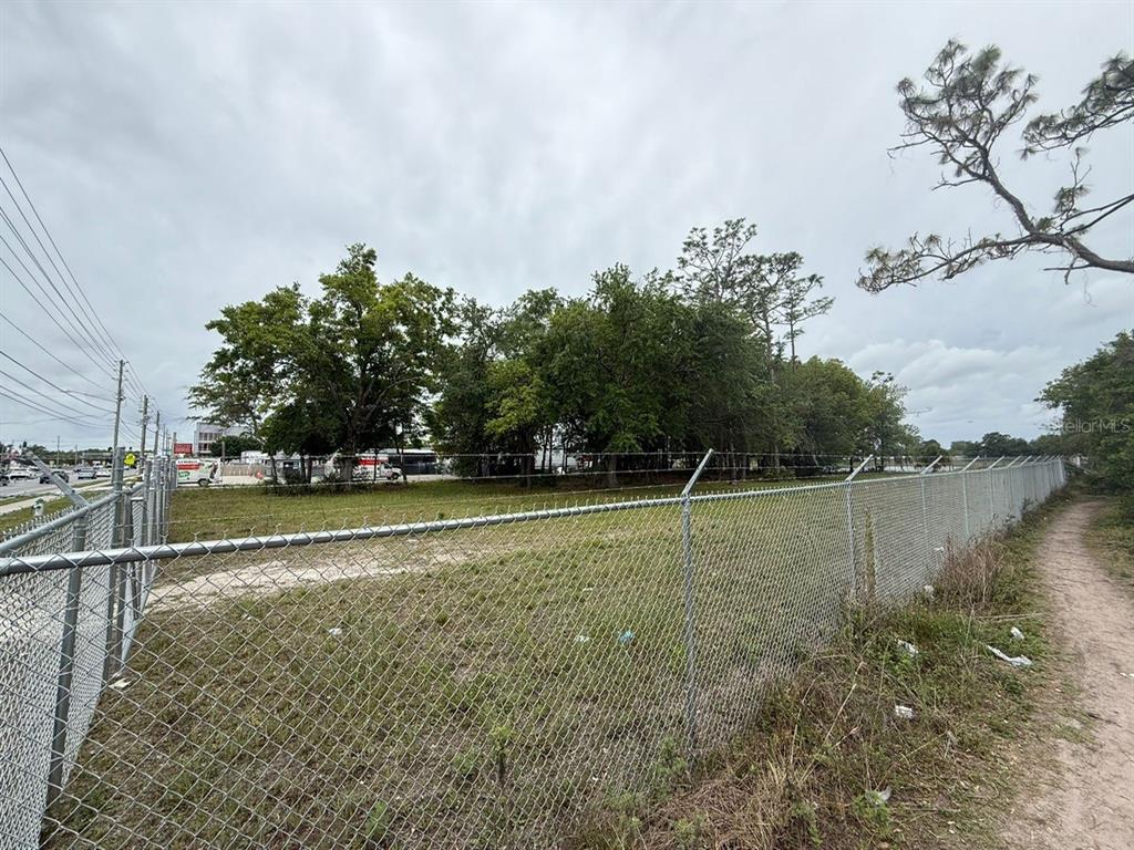 A fenced, grassy vacant lot with trees sits adjacent to a paved road — 3842 S GOLDENROD, ORLANDO, FL
