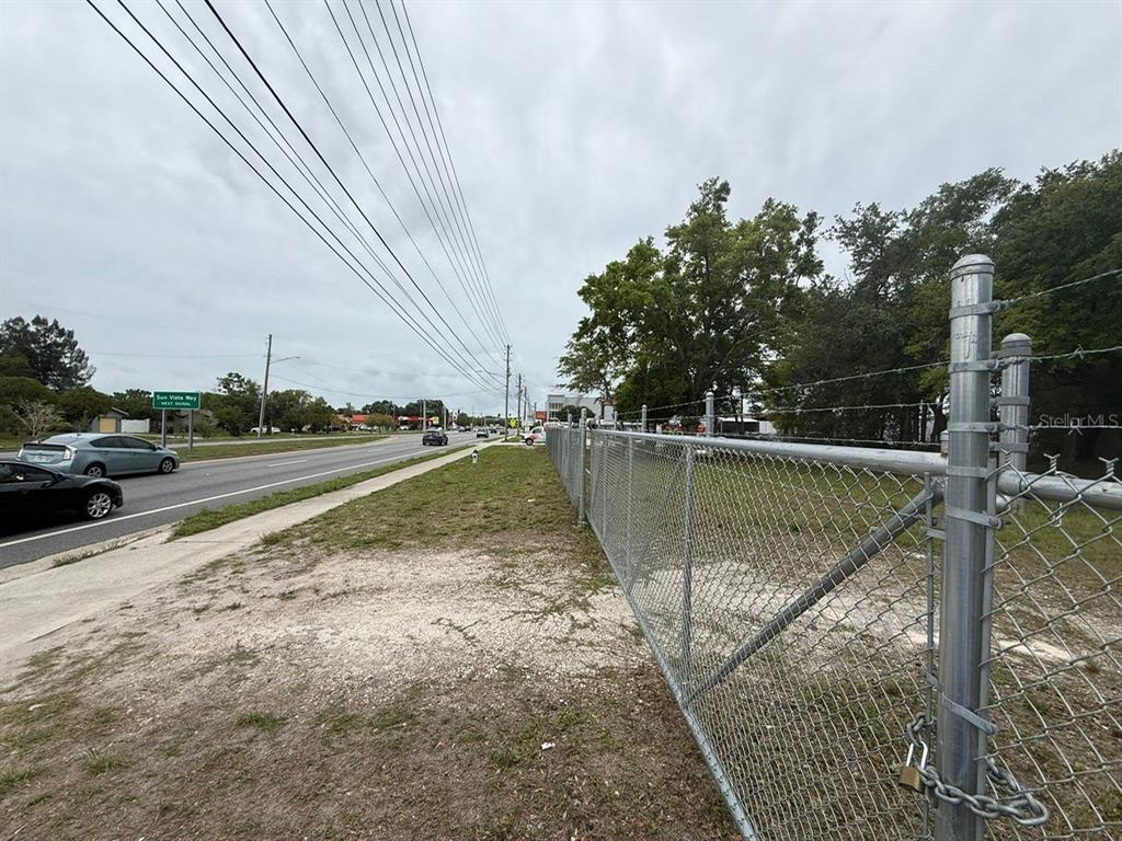 A chain-link fence borders a grassy area next to a road with passing cars — 3842 S GOLDENROD, ORLANDO, FL
