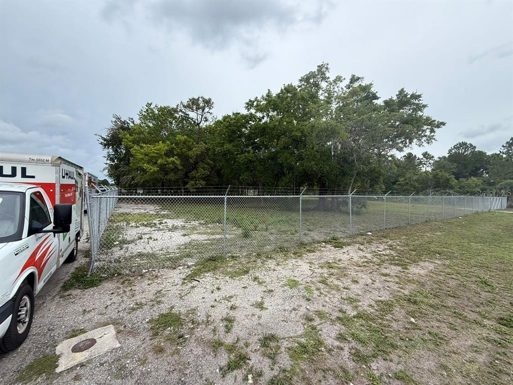 A chain-link fence encloses a vacant, grassy lot next to a parked U-Haul truck — 3842 S GOLDENROD, ORLANDO, FL