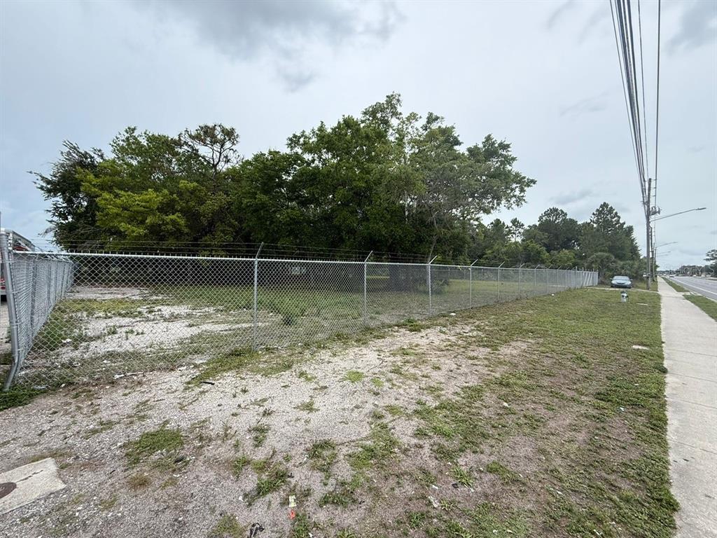 A fenced, vacant lot with trees and grass sits next to a sidewalk and road — 3842 S GOLDENROD, ORLANDO, FL
