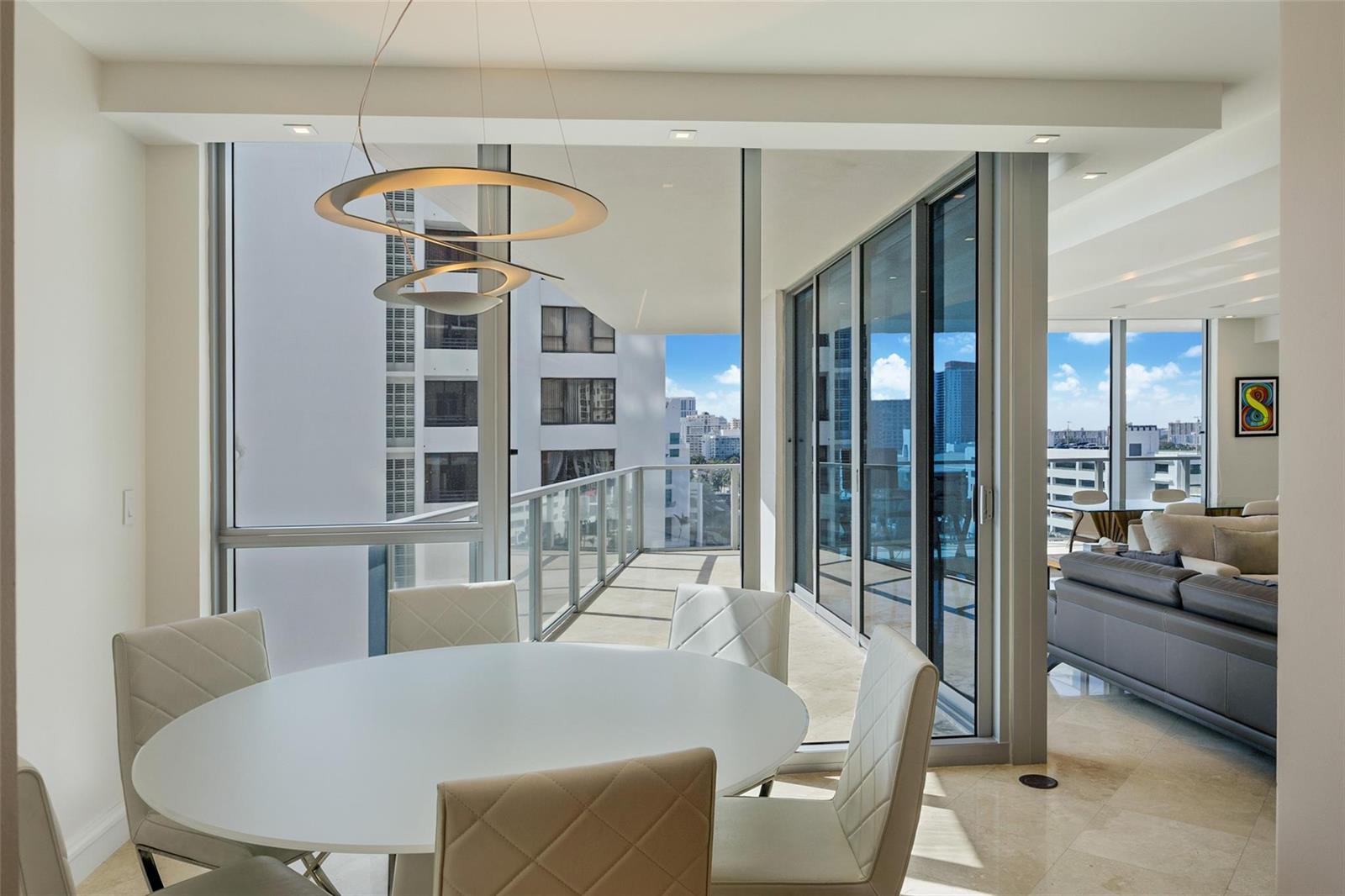A dining area with a white table and chairs overlooks a balcony and city skyline — 3101 S Ocean Drive # 902, Hollywood FL 33019, HOLLYWOOD, FL