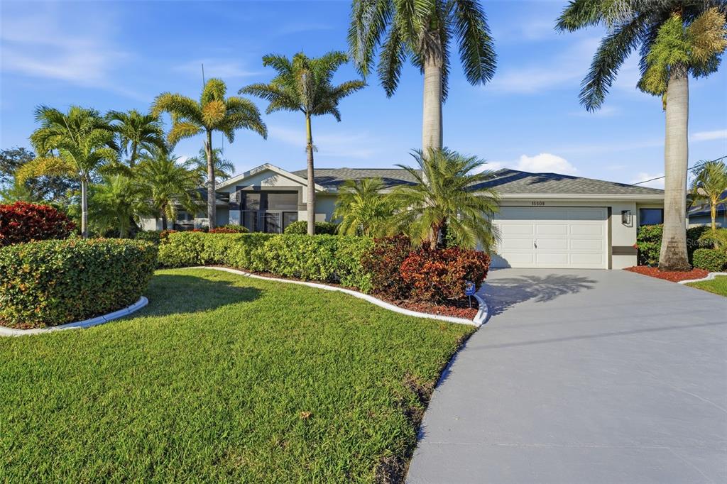 A single-story house with a white garage, palm trees, and a manicured lawn — 15508 RUSTON CIRCLE, PORT CHARLOTTE, FL