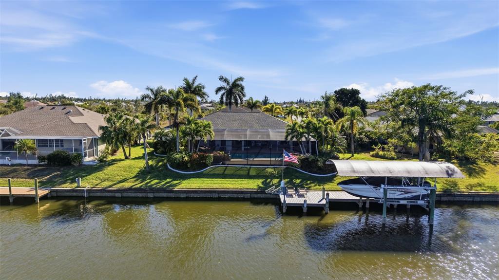 An aerial view of a waterfront house with a pool cage, dock, and boat lift — 15508 RUSTON CIRCLE, PORT CHARLOTTE, FL