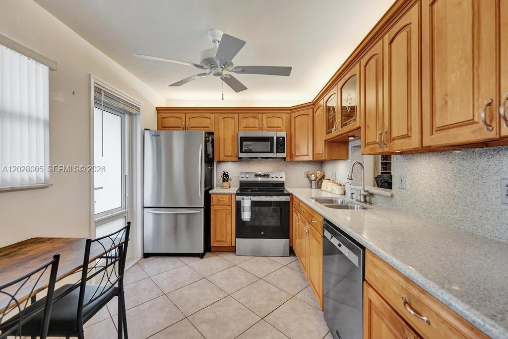 A kitchen features light wood cabinets, stainless steel appliances, and a tiled floor — 1025 SE 2nd Ave # 208, Dania Beach FL 33004, DANIA BEACH, FL