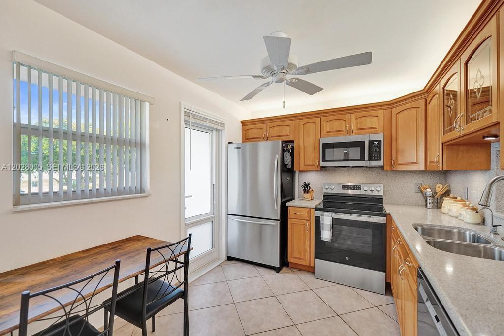 A kitchen features wood cabinets, stainless steel appliances, tile flooring, and a small dining table — 1025 SE 2nd Ave # 208, Dania Beach FL 33004, DANIA BEACH, FL