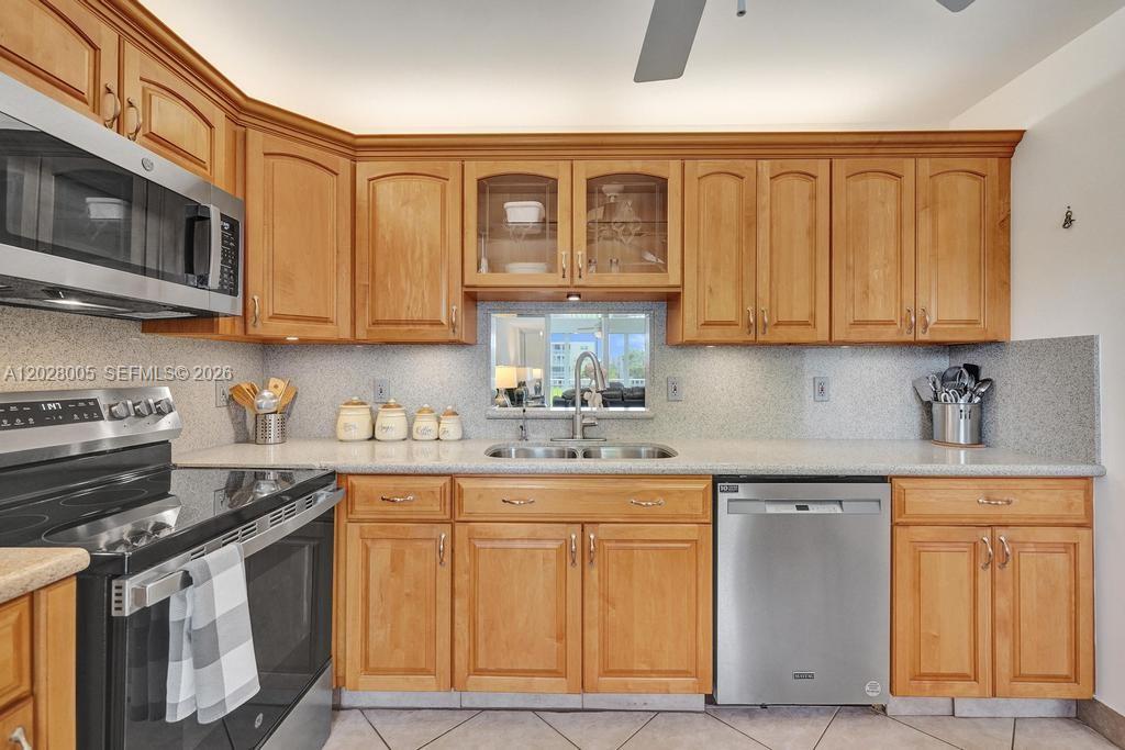A kitchen features light wood cabinets, stainless steel appliances, and a gray speckled countertop — 1025 SE 2nd Ave # 208, Dania Beach FL 33004, DANIA BEACH, FL