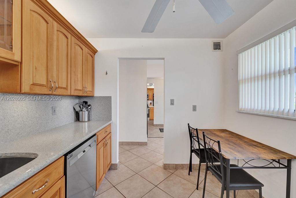 A kitchen features light wood cabinets, granite countertops, a dishwasher, and a small dining table — 1025 SE 2nd Ave # 208, Dania Beach FL 33004, DANIA BEACH, FL