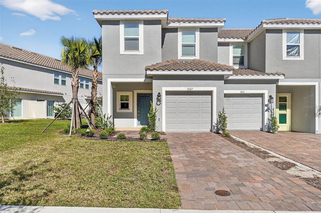 A two-story gray townhouse with a brick paver driveway and a single-car garage — 3607 MAIN HARBOR DRIVE, KISSIMMEE, FL