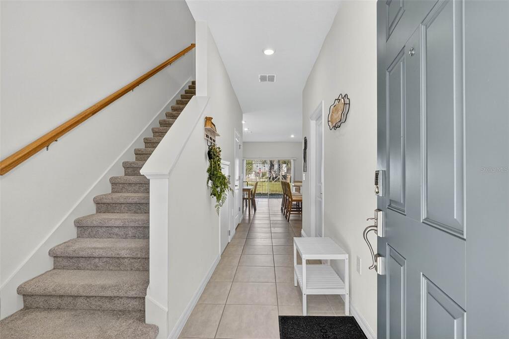 An entryway features a carpeted staircase, tile flooring, and a view toward the dining area — 3607 MAIN HARBOR DRIVE, KISSIMMEE, FL
