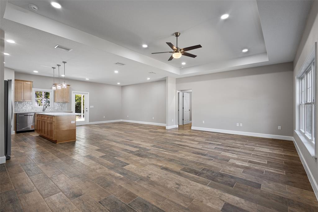 An open-concept living area features a kitchen with wood cabinets and wood-look tile flooring — 9100 DORIE DRIVE, TRENTON, FL
